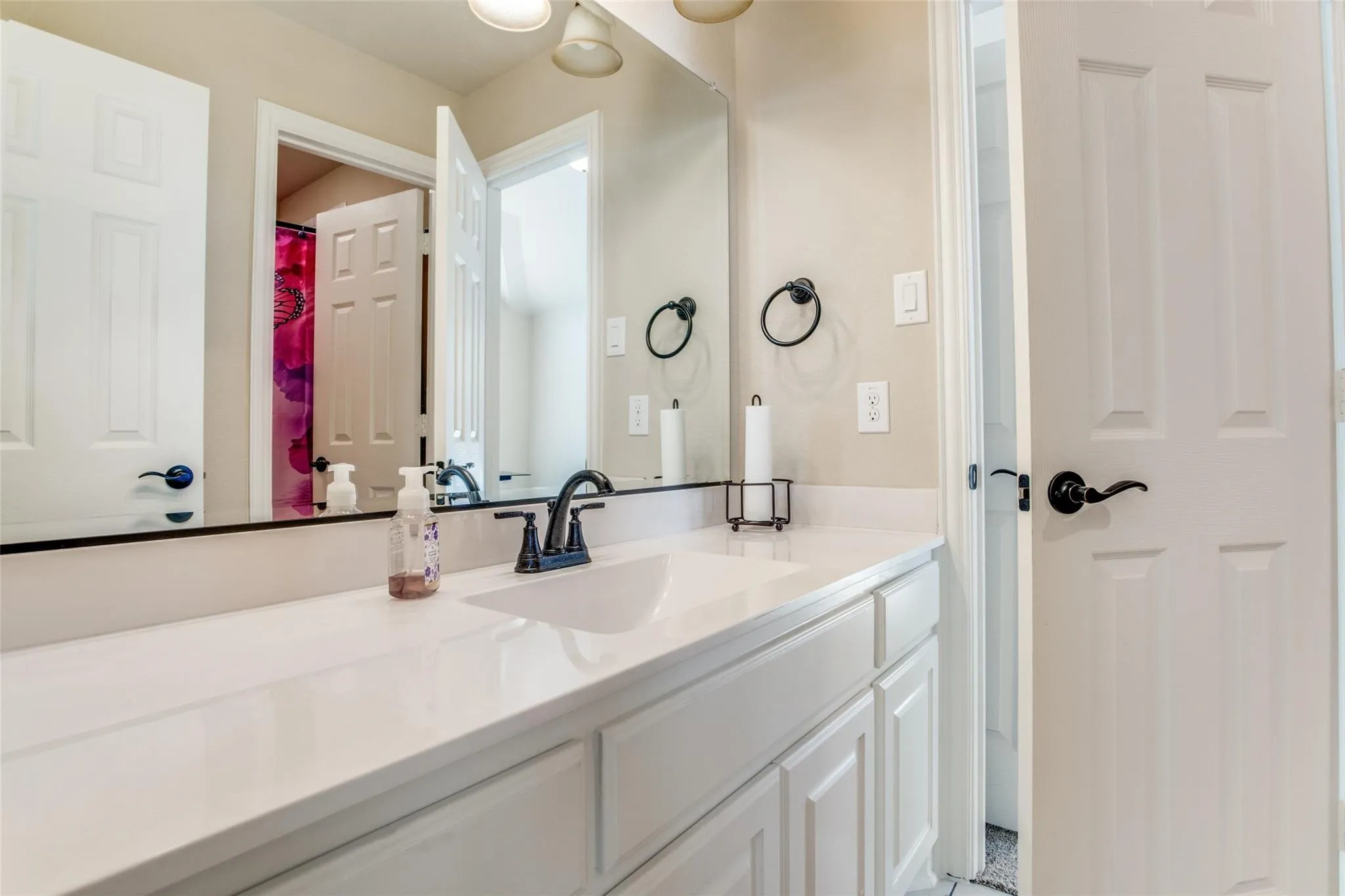 White vanity with shaker-style cabinetry, an integrated sink, and a black faucet