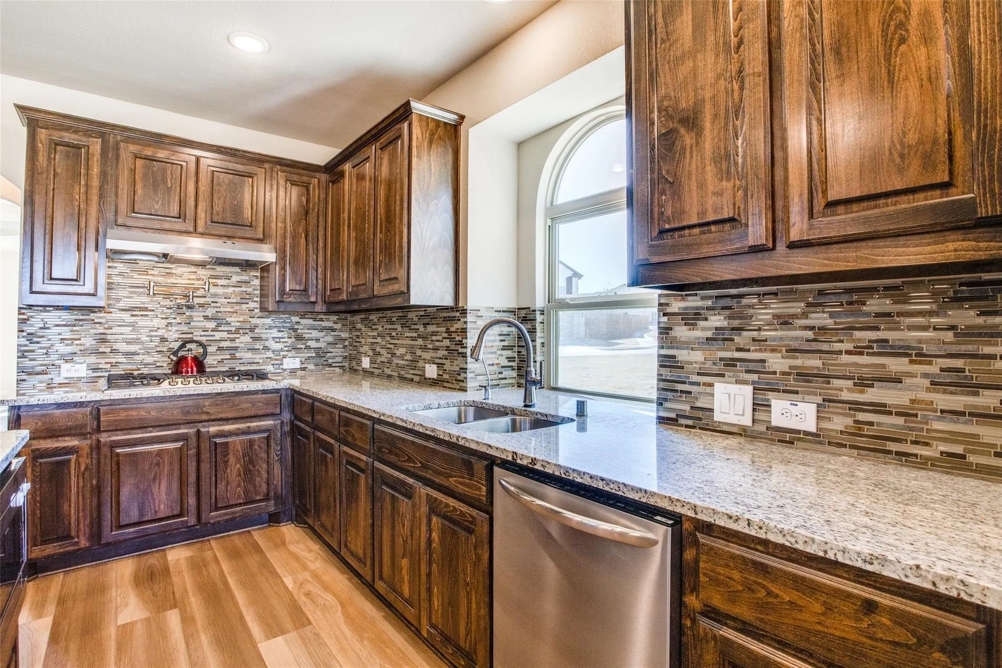 Kitchen featuring wood-finish cabinetry, granite countertops, and a mosaic tile backsplash