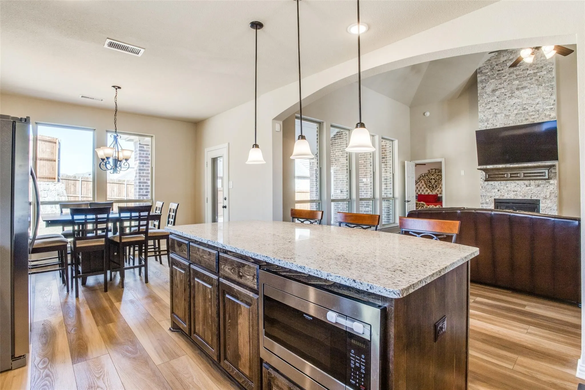 Kitchen island with a light-toned countertop, integrated microwave, and pendant lighting