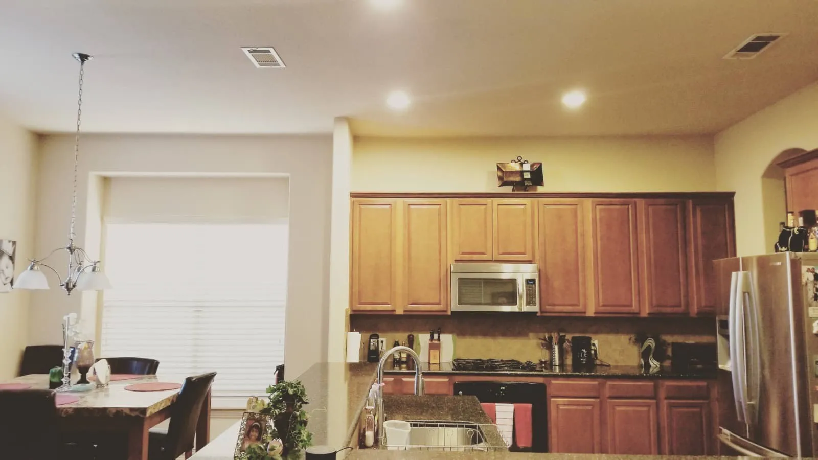 Open-concept kitchen with recessed lighting, wood-finish cabinetry, stainless steel appliances, and a breakfast bar