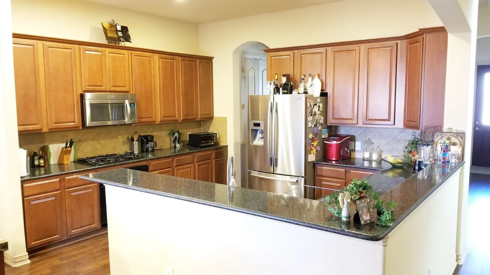 Kitchen featuring a breakfast bar with stone countertops, wood-finish cabinetry, stainless steel appliances, and tile backsplash