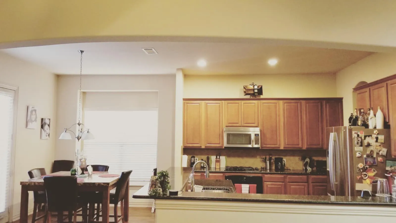 Kitchen and dining area featuring wood-finish flooring, wood cabinetry, built-in stainless steel microwave, and recessed lighting