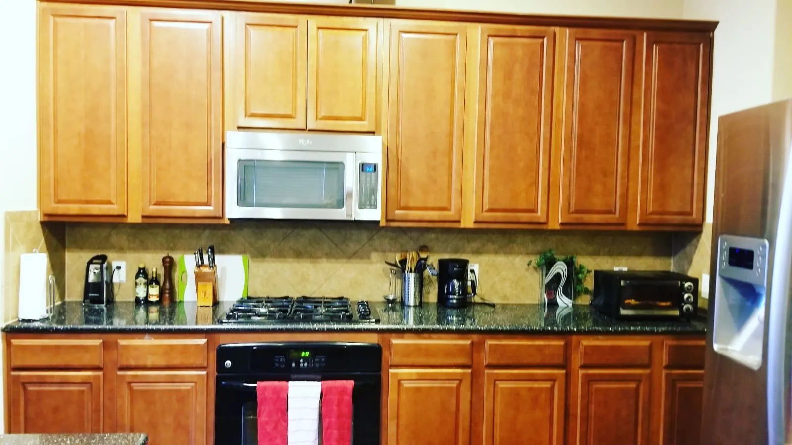 Kitchen featuring abundant wood-finish cabinetry, dark speckled countertops, and a tiled backsplash