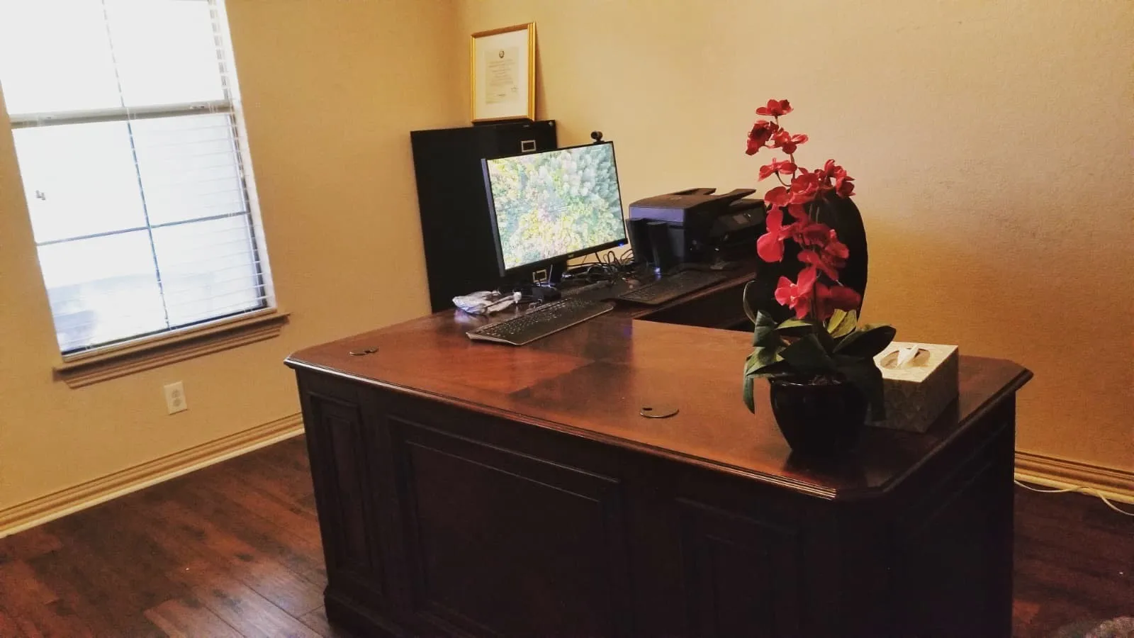 Room featuring wood-finish flooring, neutral wall paint, a window with horizontal blinds, and a dark-toned built-in desk