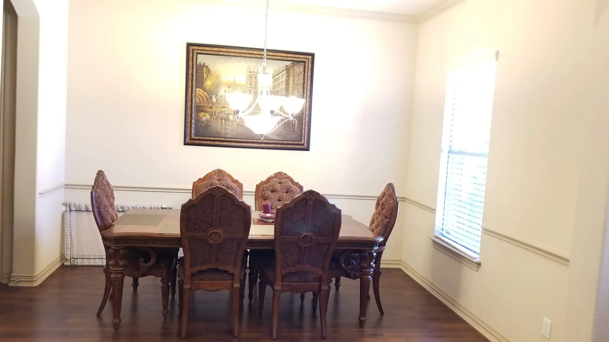 Dining area featuring wood-finish flooring, a wall-mounted chandelier, and a single window with blinds