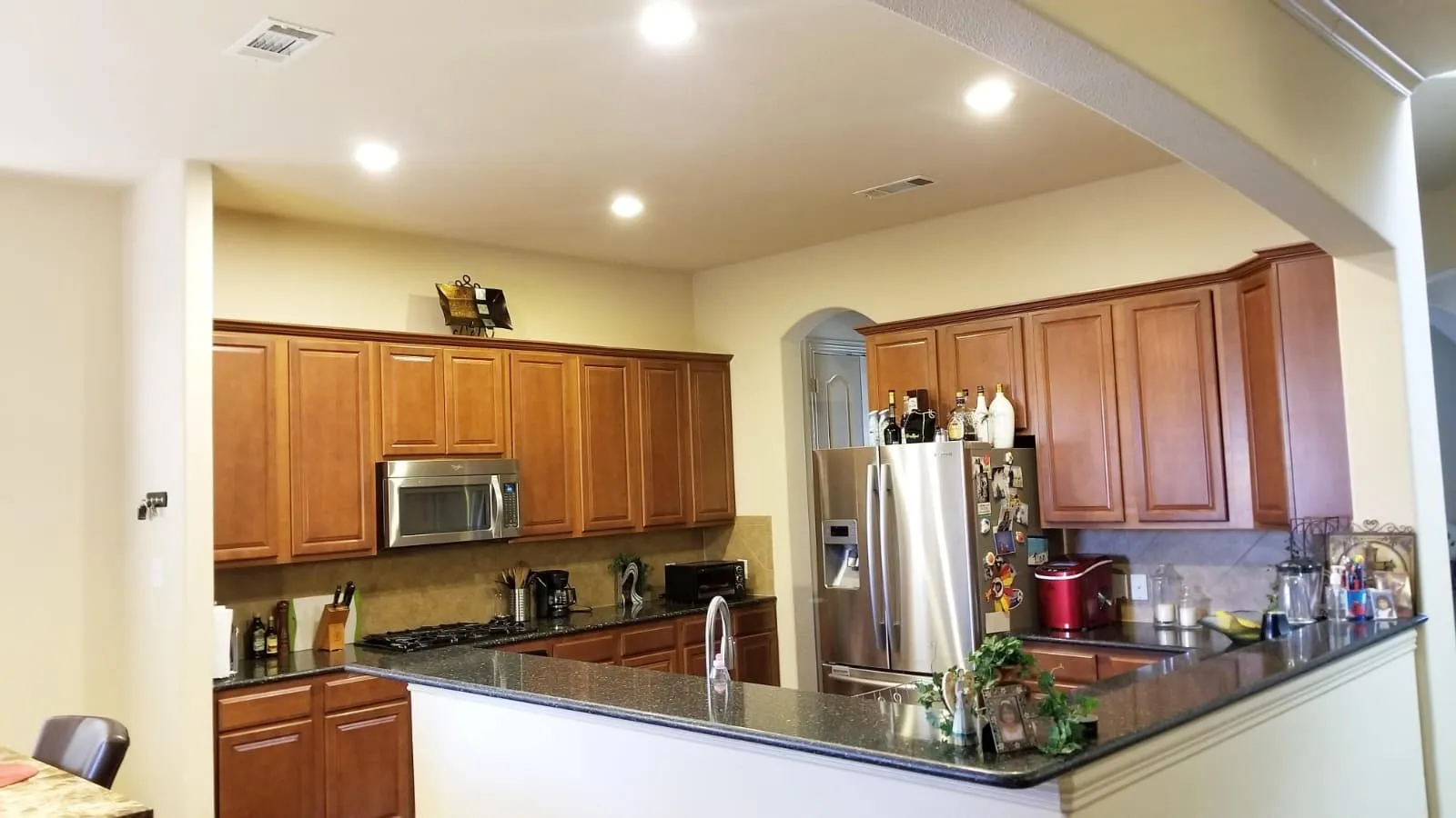Kitchen featuring wood cabinetry, dark countertops, a built-in microwave, and recessed lighting