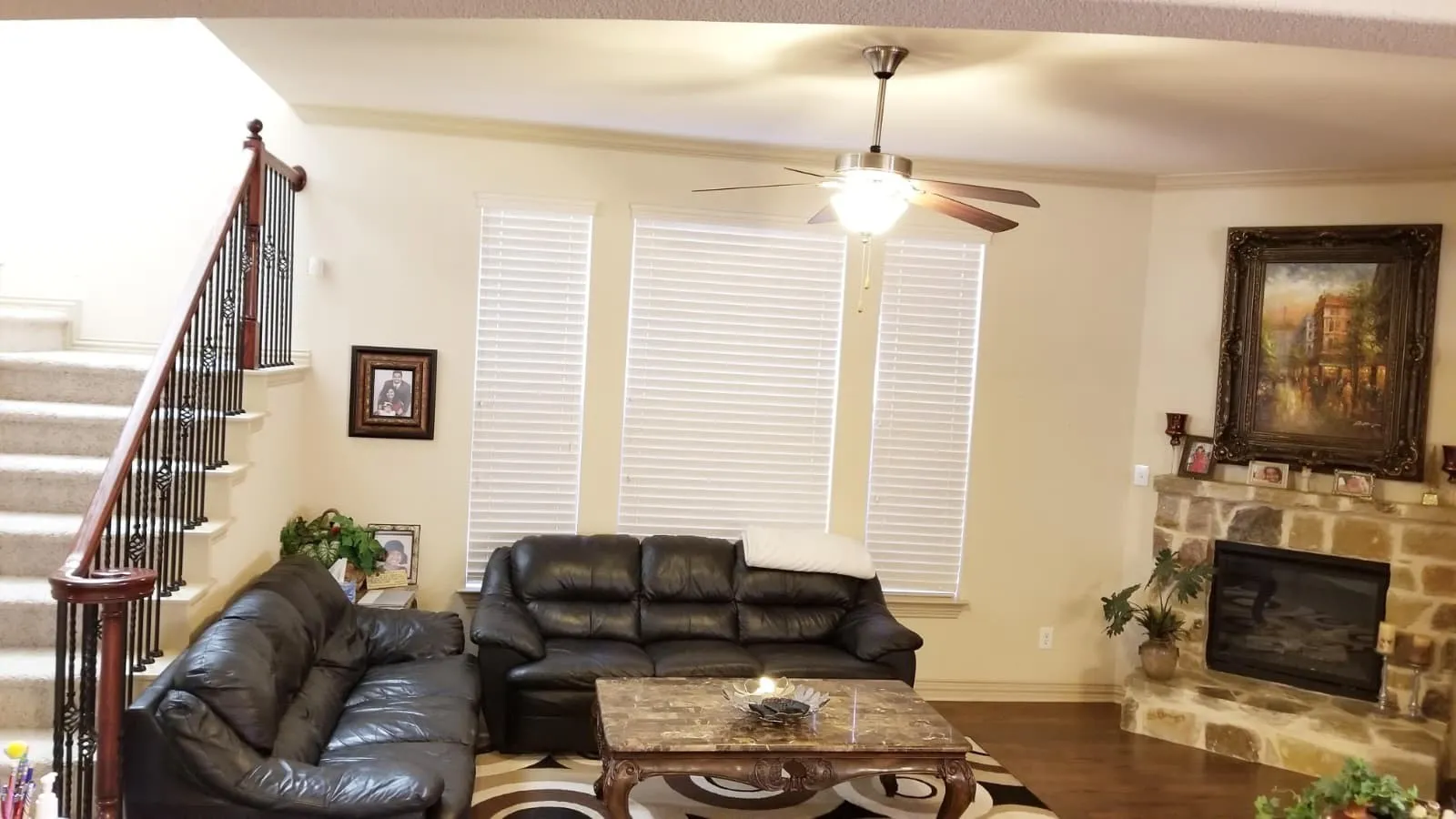 Living area featuring a stone fireplace, wood-finish flooring, and multiple windows with blinds