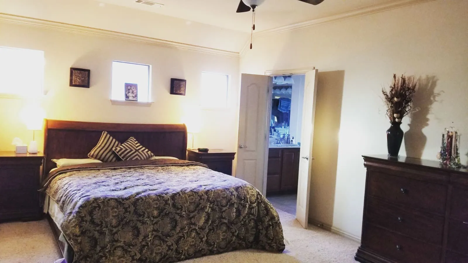 Spacious bedroom featuring neutral wall tones, crown molding, a ceiling fan, and carpeted flooring