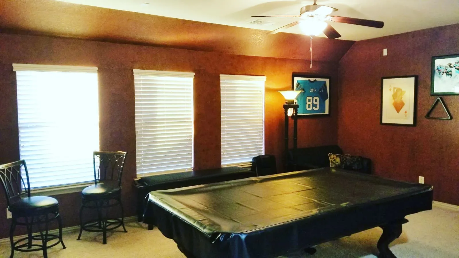 Spacious room featuring three windows with white blinds, textured accent walls, and a ceiling fan with integrated lighting