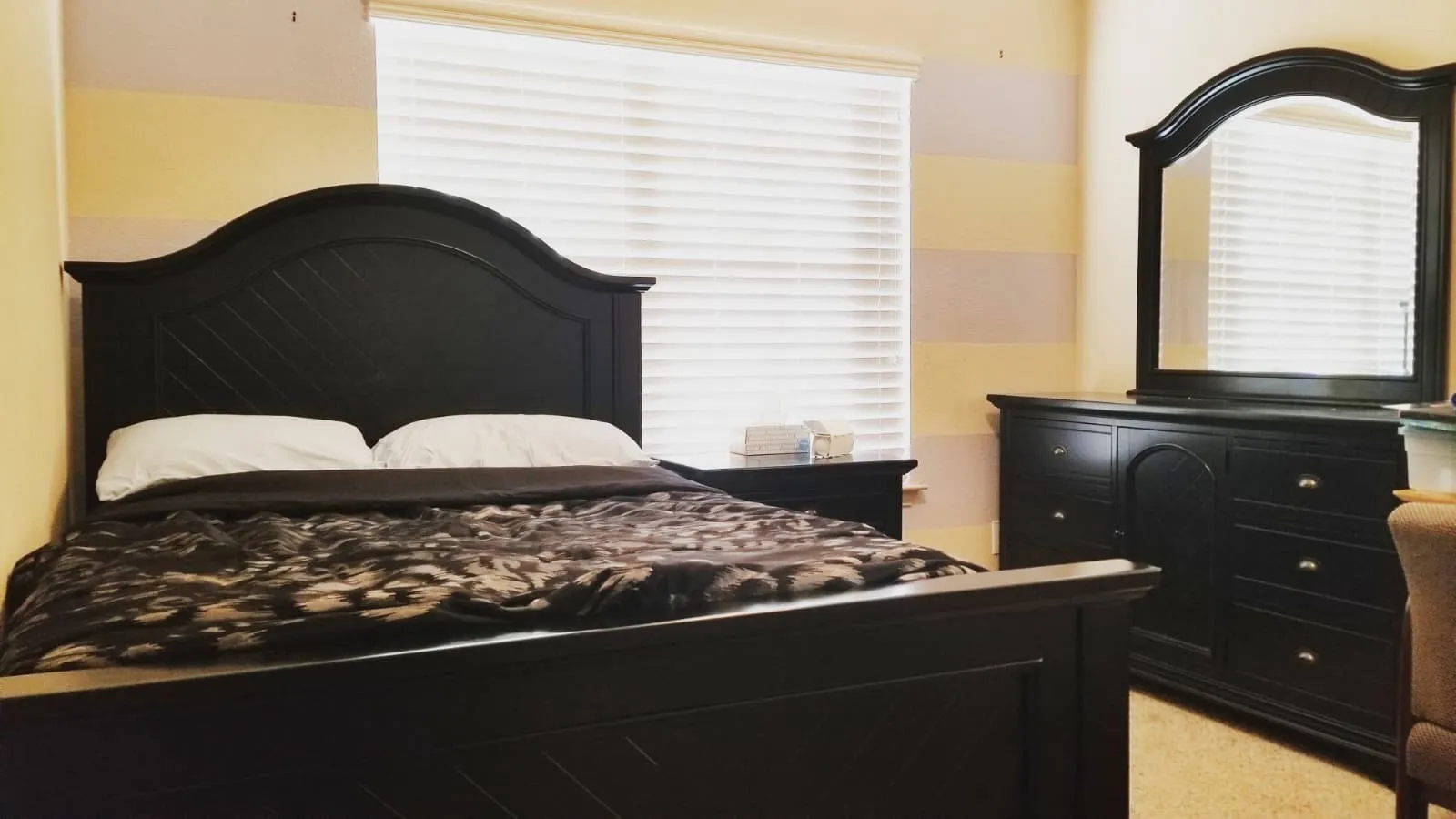 Room featuring a window with horizontal blinds and light-colored walls with striped accent