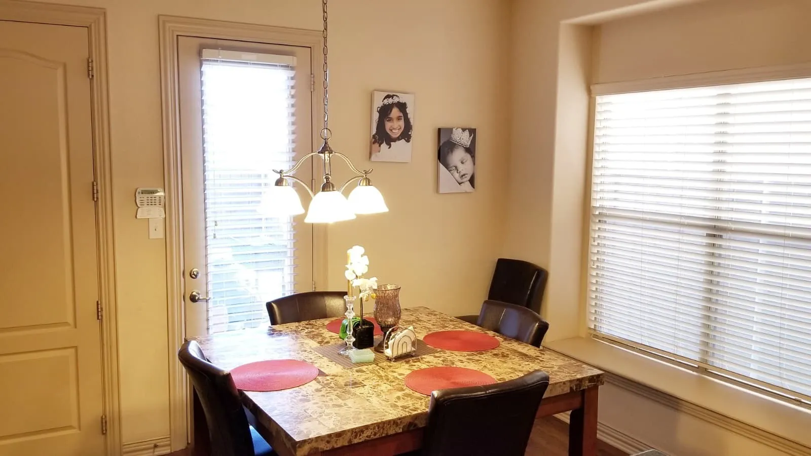 Dining area featuring a contemporary four-light chandelier, a large window with horizontal blinds, and a built-in window sill