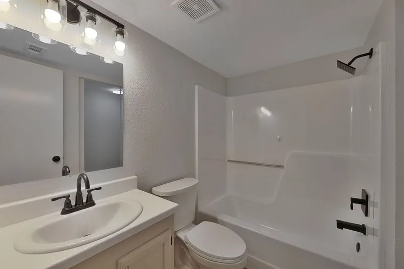 Bathroom featuring a single vanity with an integrated sink, bronze-finish faucet, and overhead bar lighting
