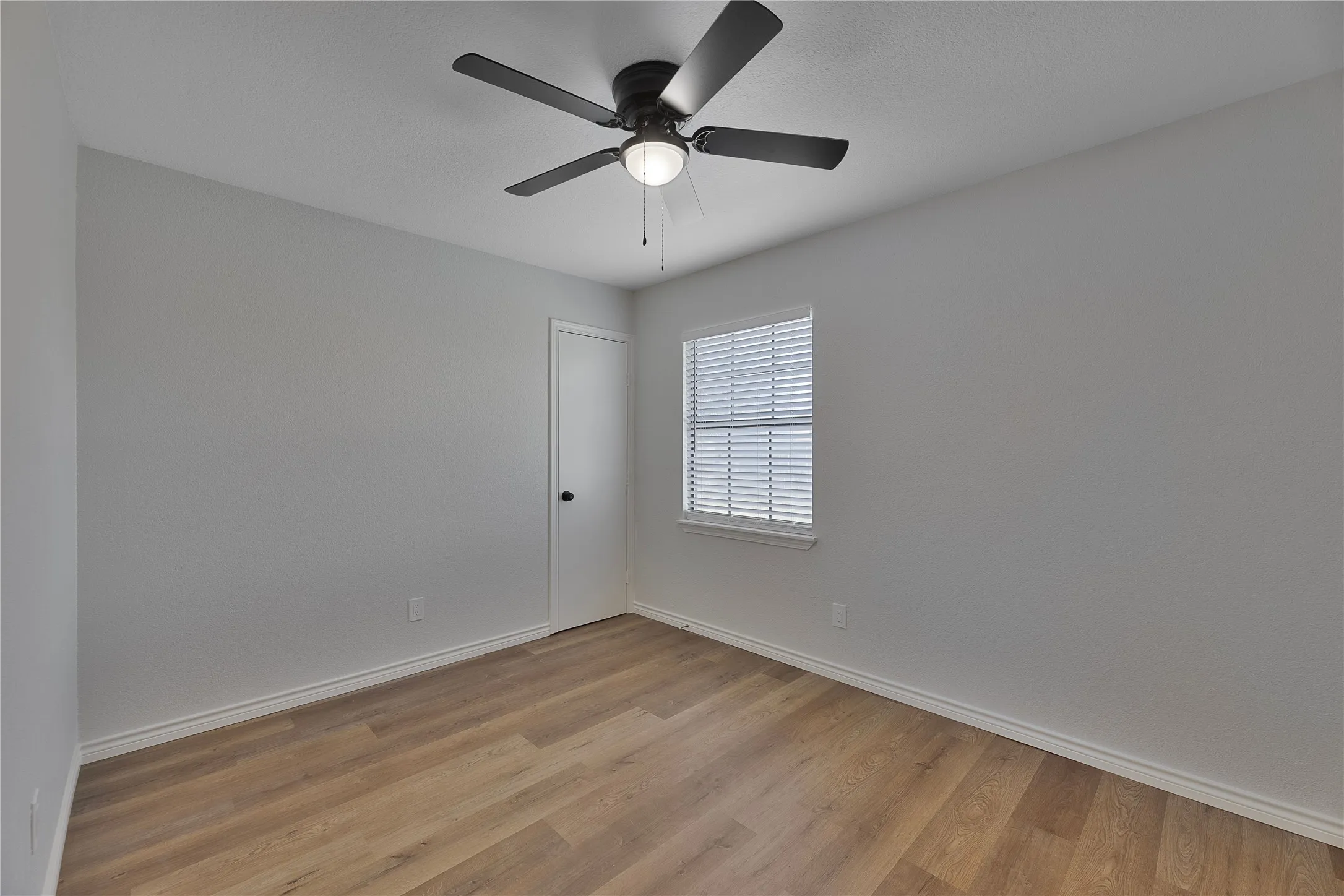 Neutral-toned room featuring wood-finish flooring and white baseboards