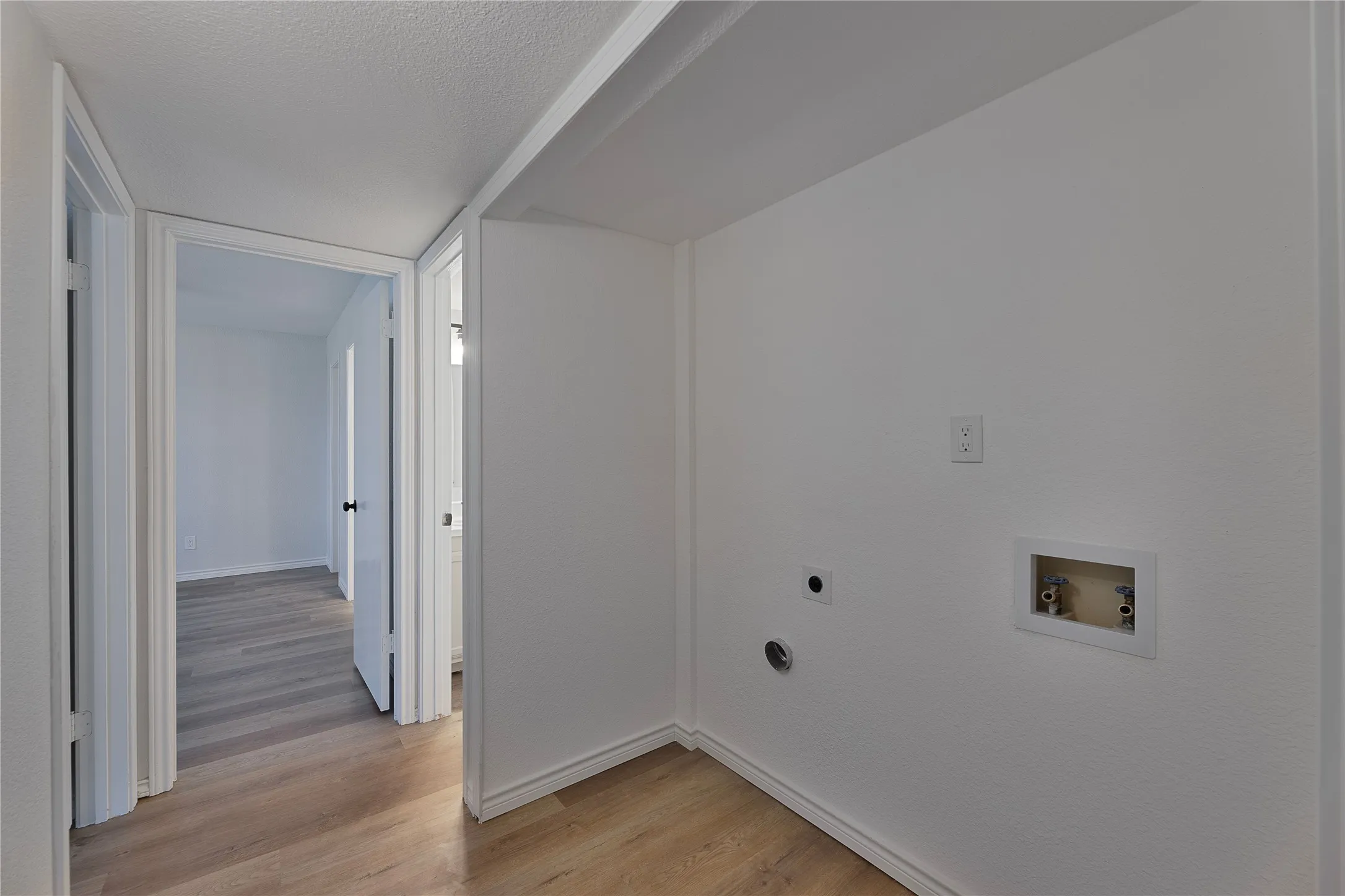 Dedicated laundry area featuring hookups for washer and dryer, light wood-finish flooring, and crisp white walls