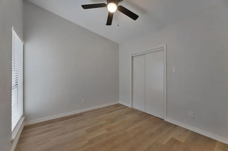 Interior room featuring vaulted ceilings, wood-finish flooring, and a ceiling fan with integrated lighting