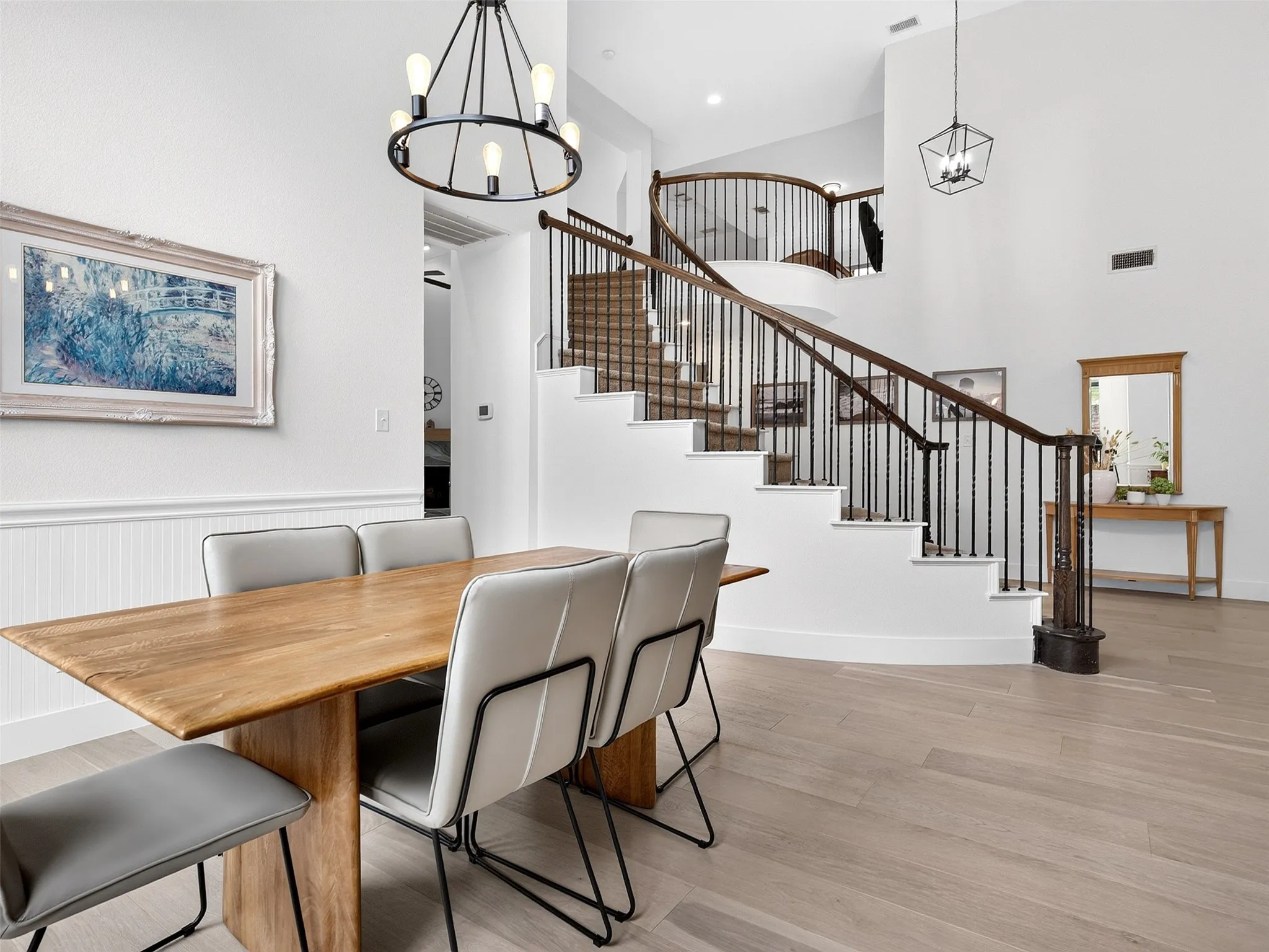 Open concept interior with a grand curved staircase featuring dark wood handrails and wrought iron balusters
