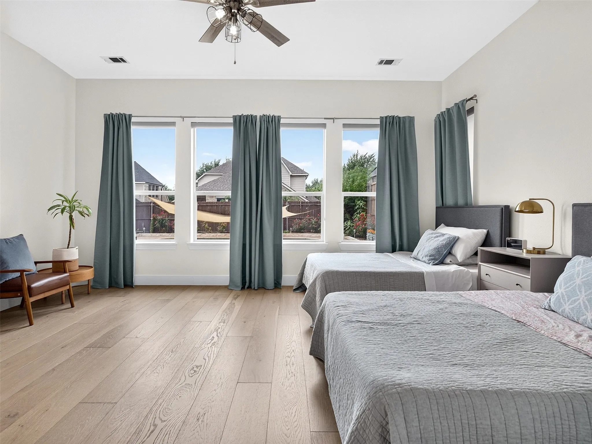 Spacious room featuring light wood-finish flooring, a contemporary ceiling fan, and multiple windows