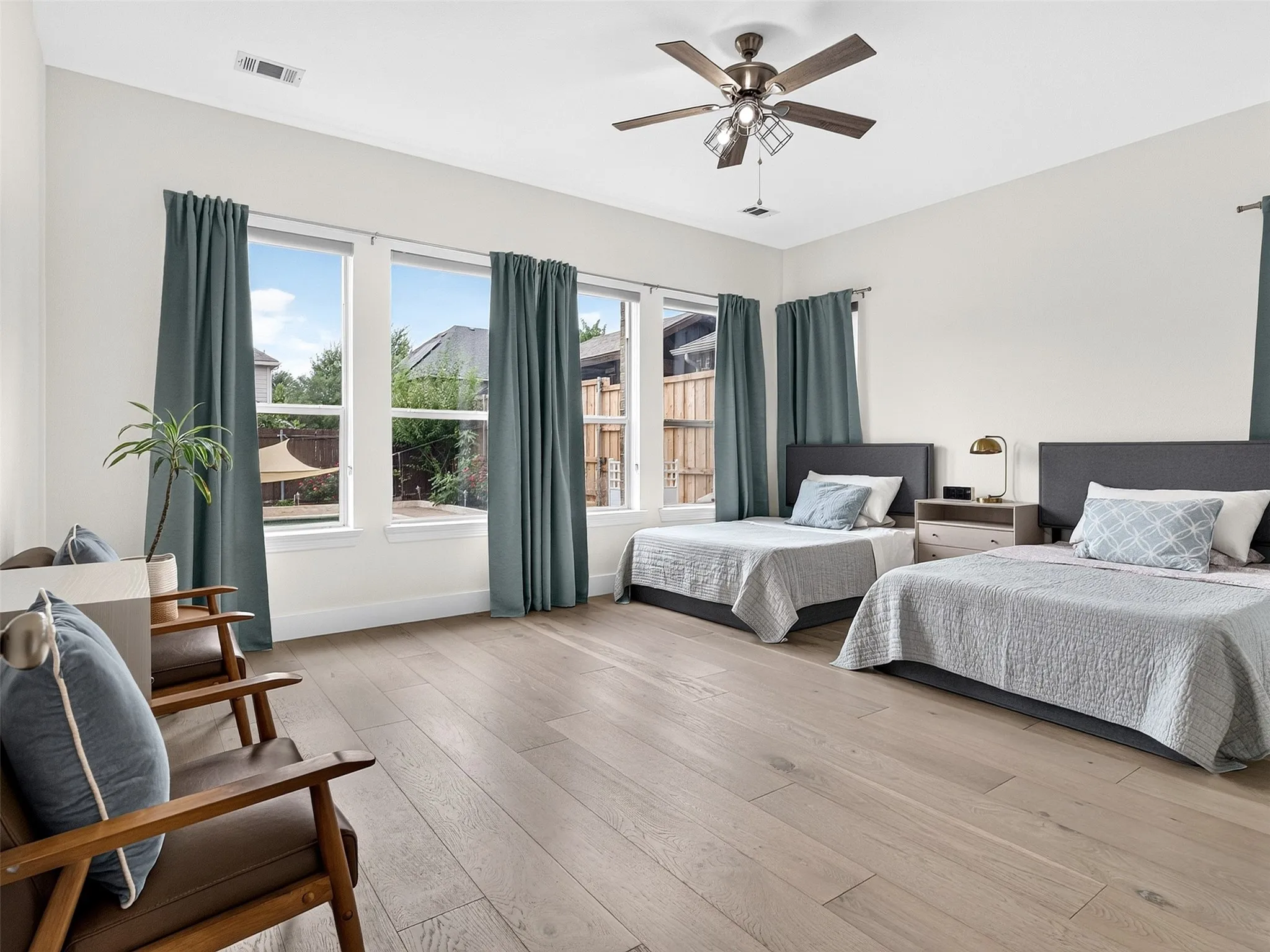 Spacious room featuring light wood-finish flooring, high ceilings, and a ceiling fan with integrated lighting