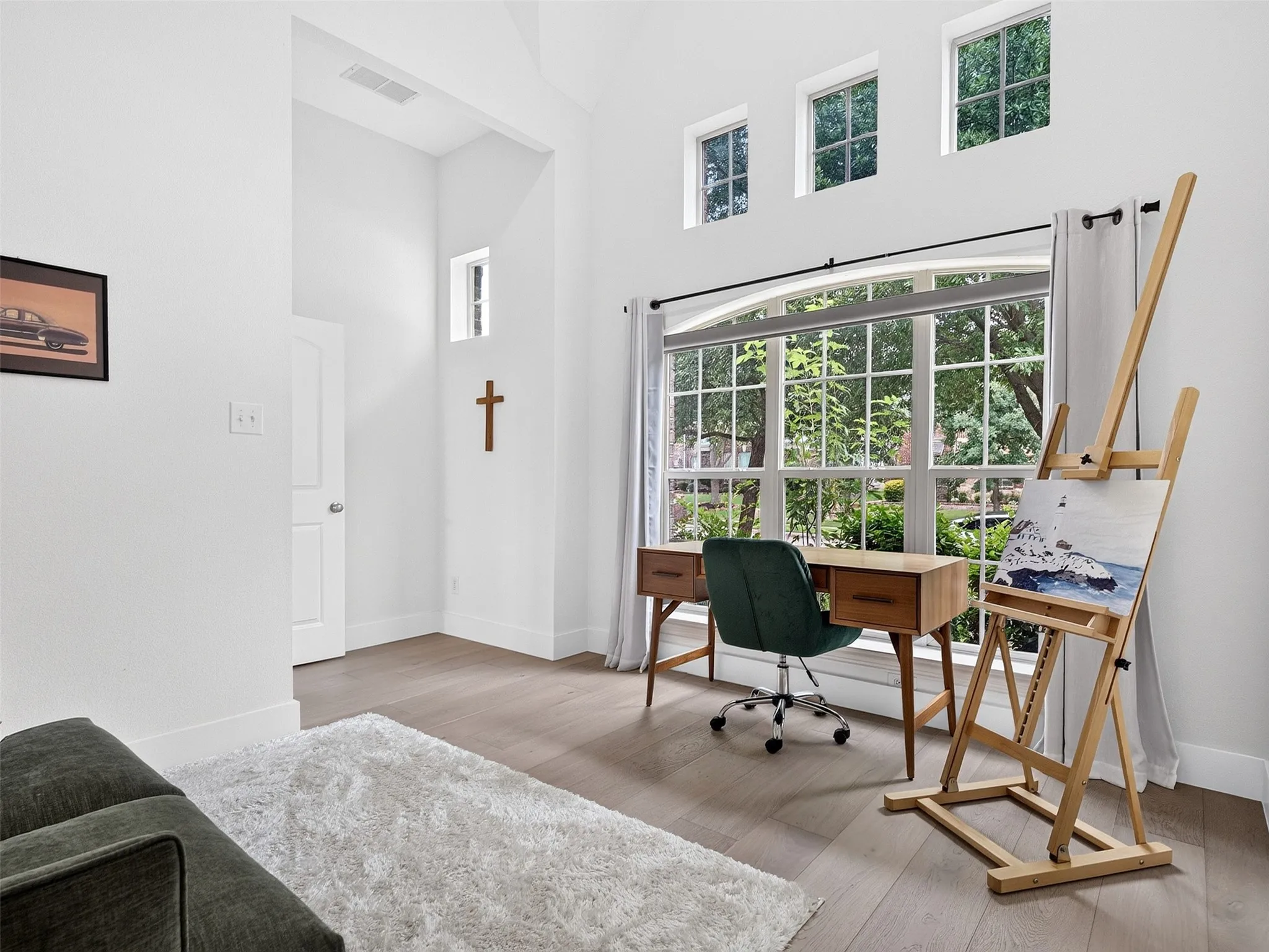 Spacious room featuring high ceilings, light wood-finish flooring, and multiple windows including transom windows