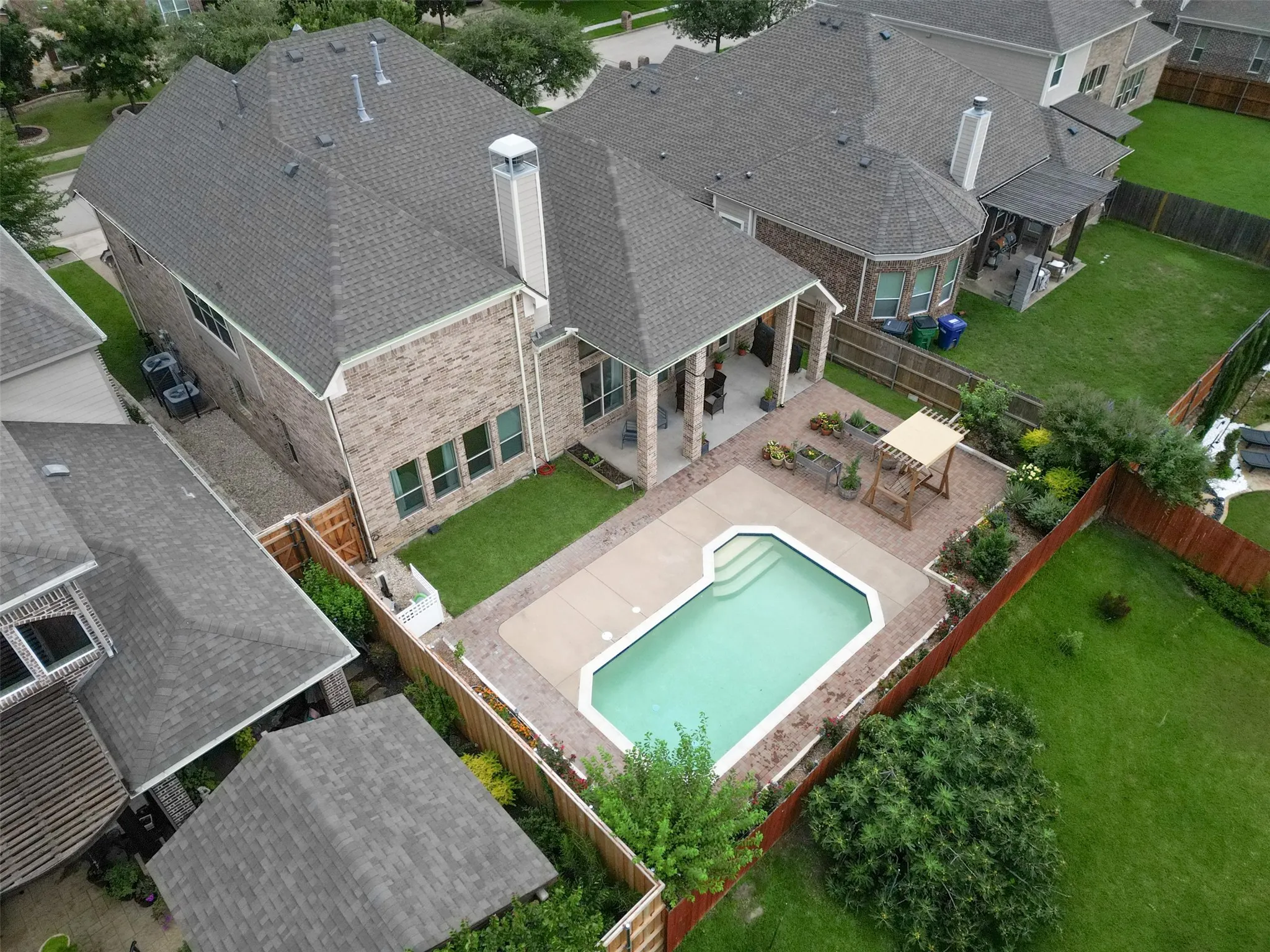 Backyard oasis featuring an in-ground swimming pool, an expansive patio, and an outdoor pergola structure