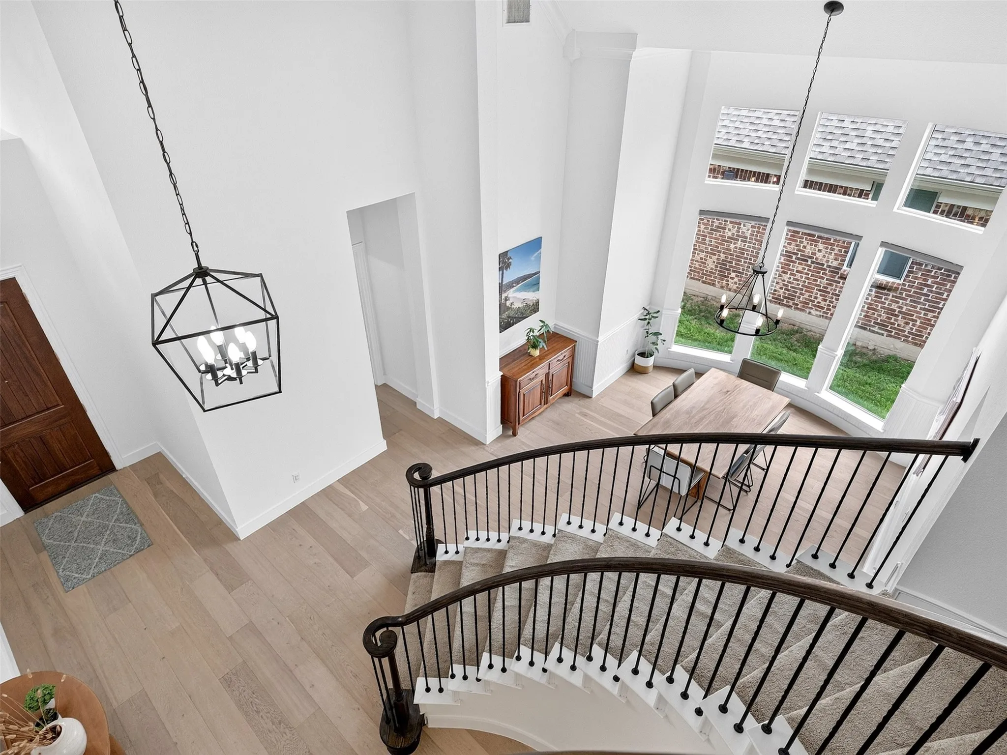 Grand curved staircase with dark wood handrail and black iron balusters