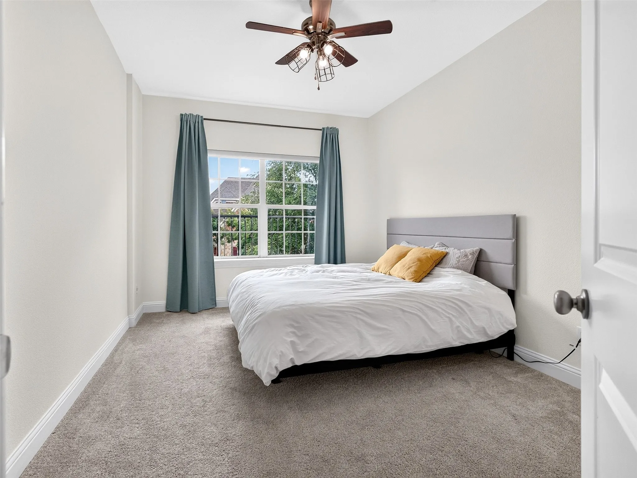 Carpeted room featuring a large window with white muntins, a ceiling fan with light fixture, and white trim
