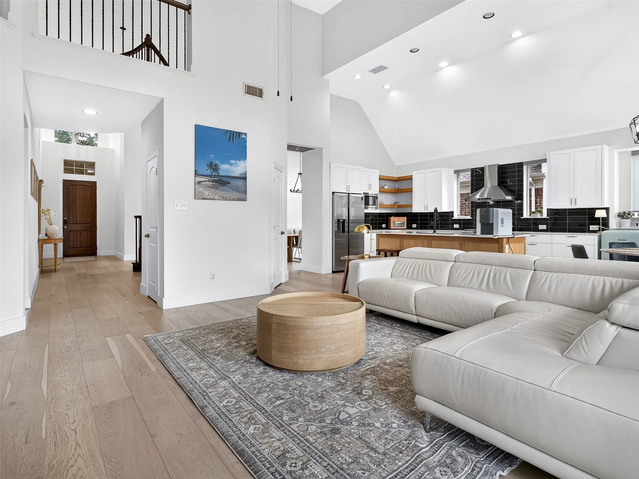 Vaulted ceiling living area featuring light wood-finish flooring, recessed lighting, and an open-concept design