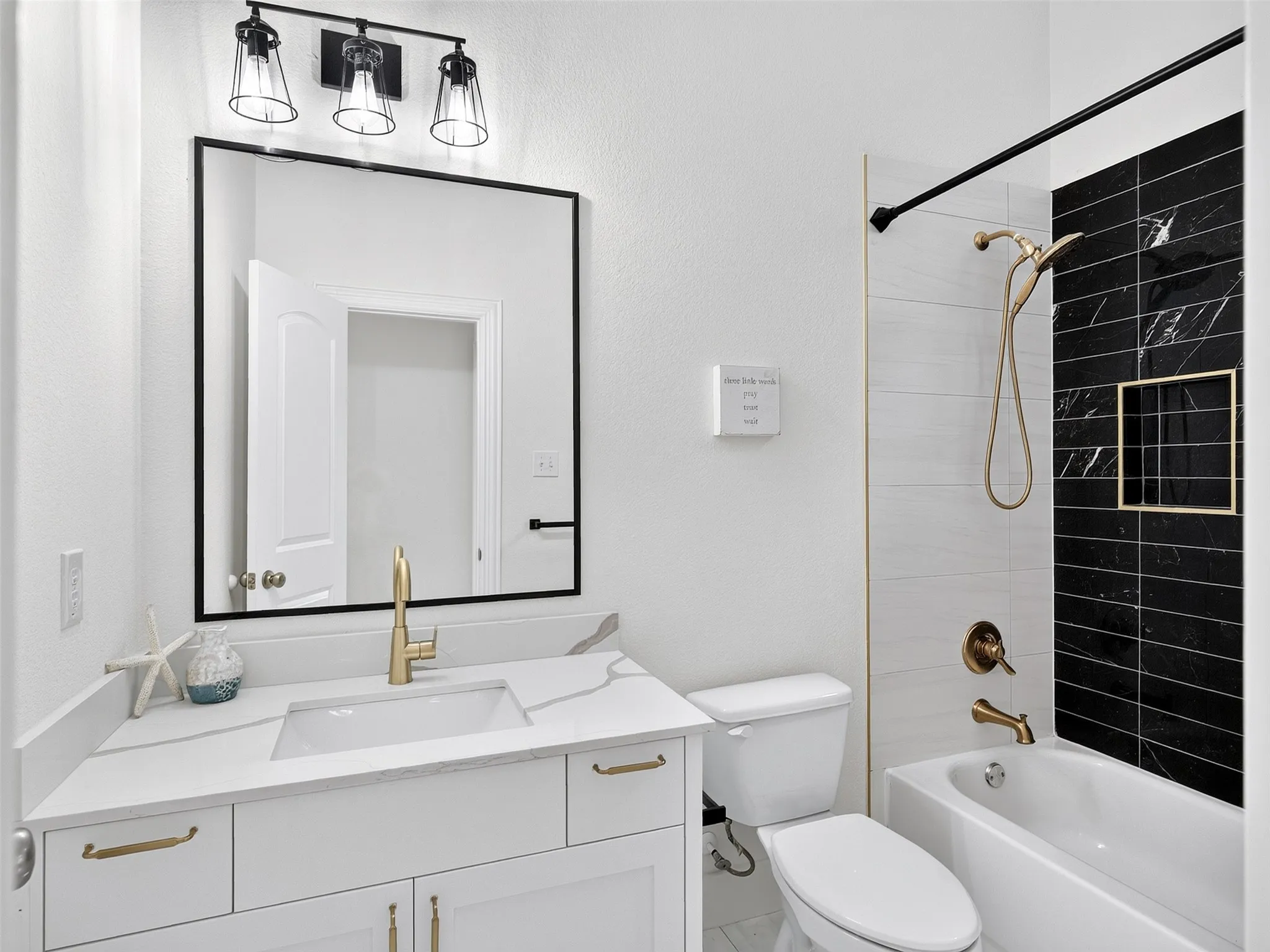 Bathroom featuring a white vanity with a white countertop, under-mount sink, and gold-finish faucet