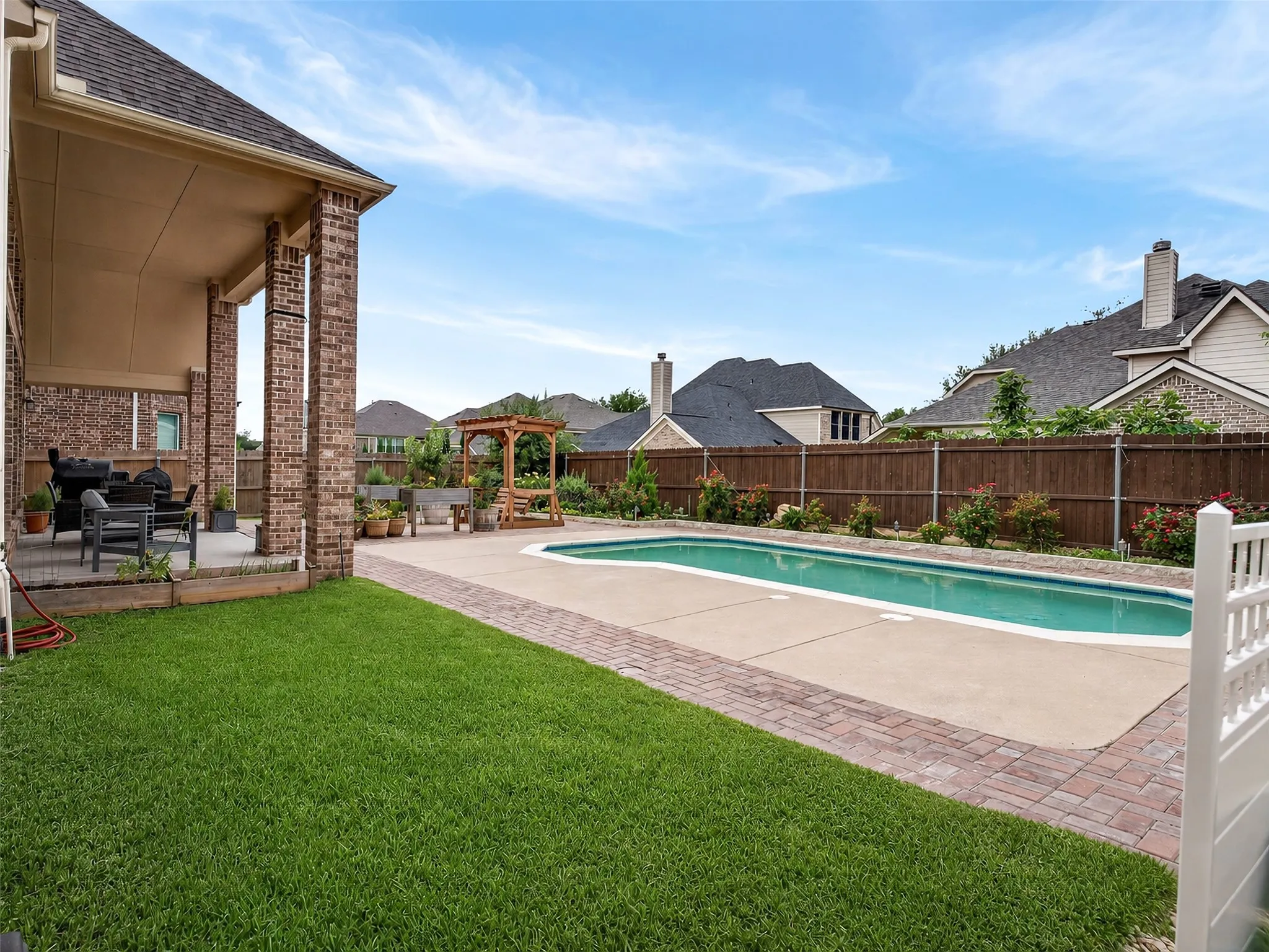 Expansive backyard featuring a rectangular swimming pool, concrete patio, and mature landscaping