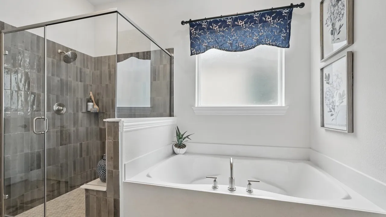 Spacious bathroom featuring a built-in corner soaking tub with deck-mounted fixtures, a separate glass-enclosed shower with vertical tile surround, and a frosted window providing natural light