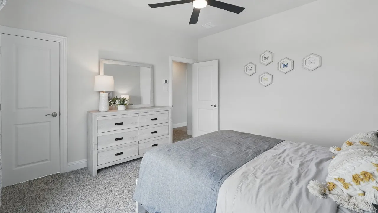 Bedroom featuring neutral gray wall paint, gray carpet flooring, a black ceiling fan with light, and white interior doors