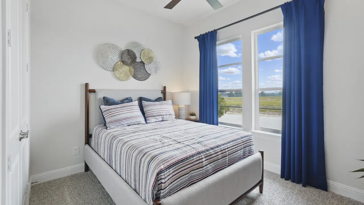 Bright room featuring two large windows, white walls, gray carpeting, a multi-paneled door, and a ceiling fan
