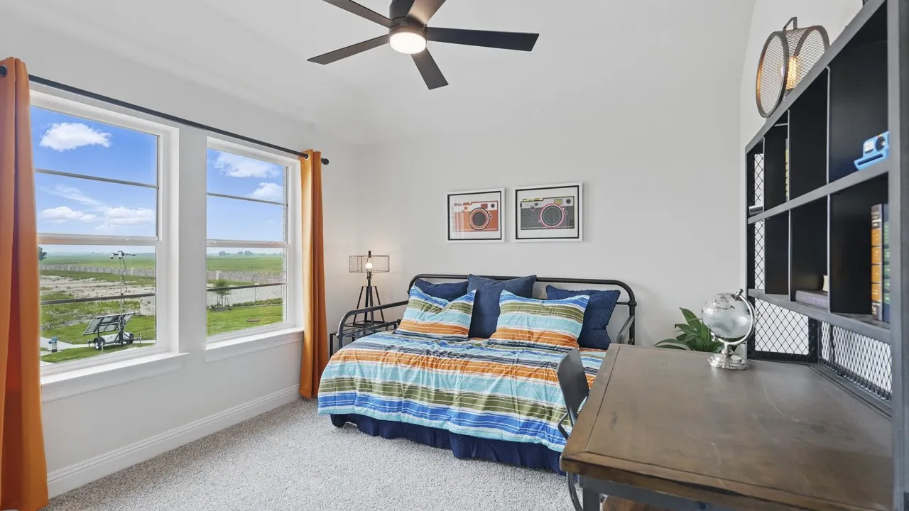 Bright room featuring two large windows, a ceiling fan with integrated lighting, and light-colored carpeting