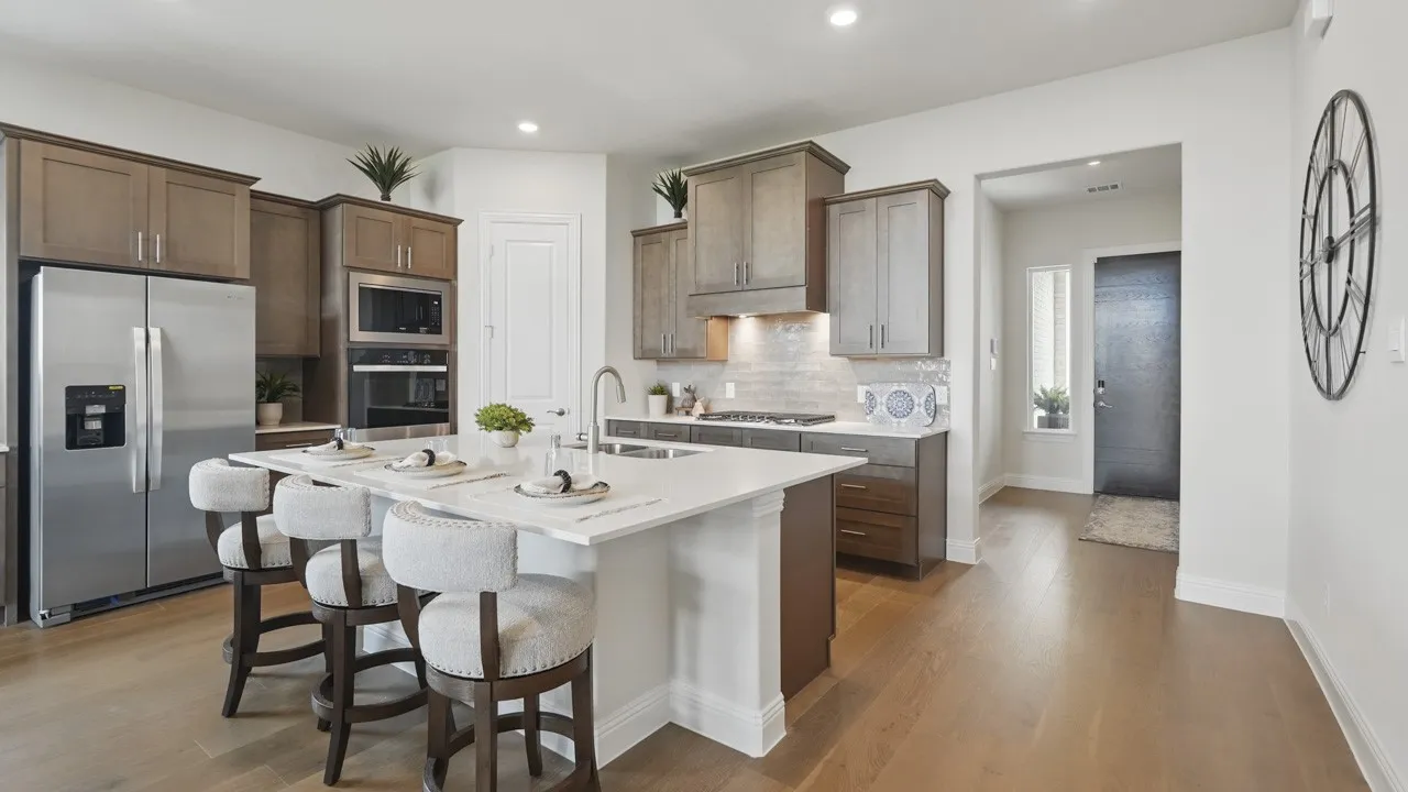 Spacious kitchen with a large central island, stainless steel appliances, wood-finish flooring, recessed lighting, and a white countertop