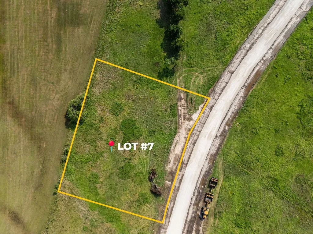Aerial view showcasing a rectangular lot with visible boundary lines, bordered by a concrete road