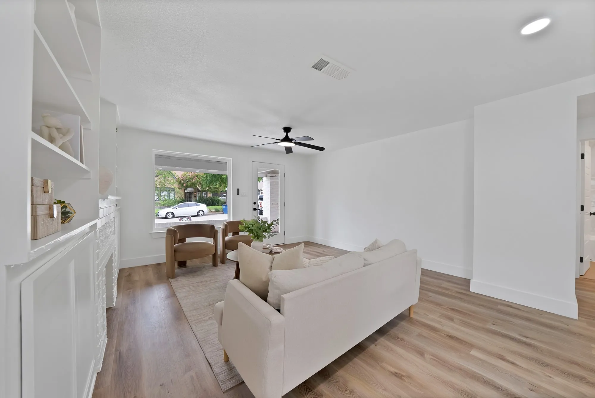 Bright living space featuring wood-finish flooring, a contemporary ceiling fan, and a large window