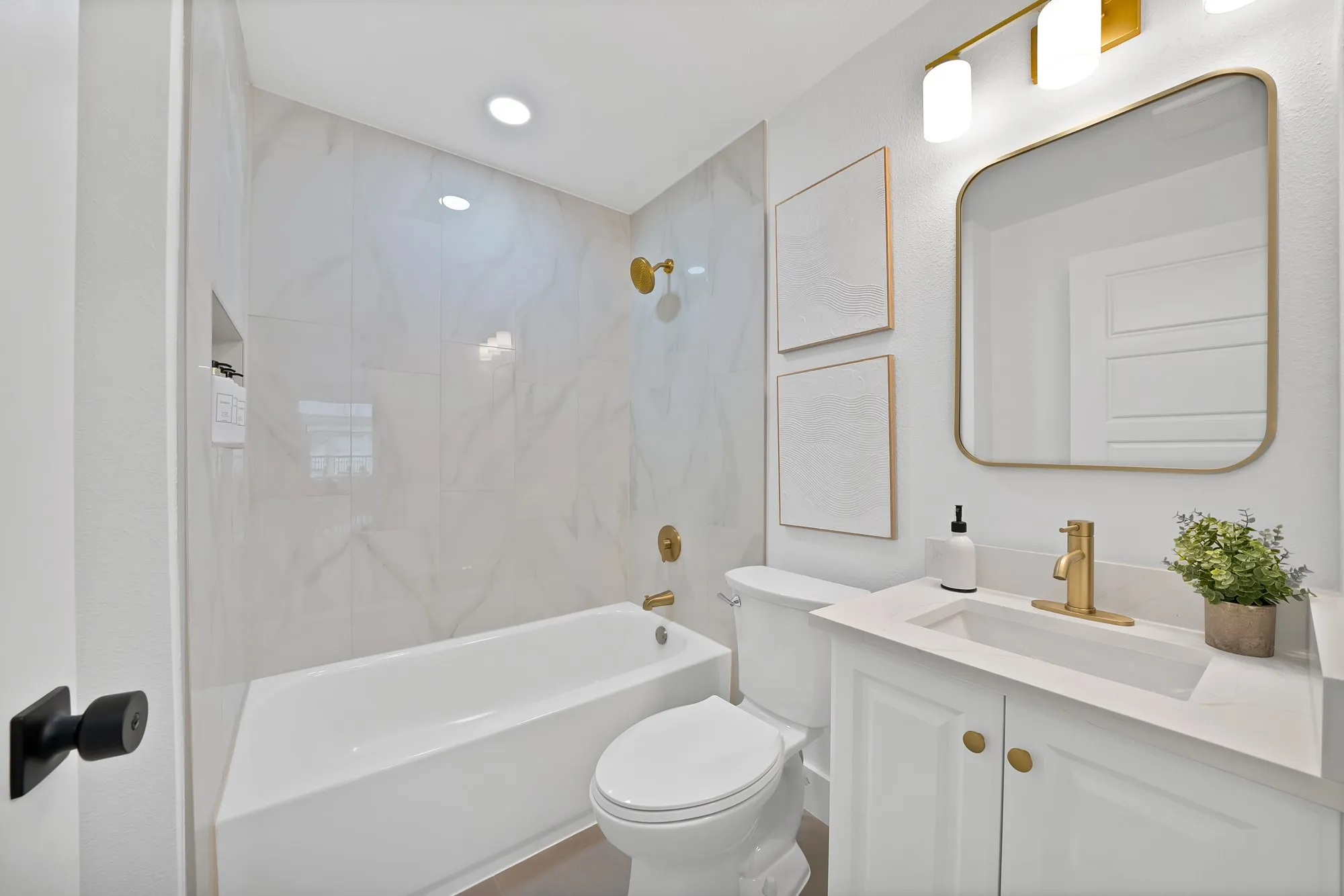 Contemporary bathroom featuring a tub and shower combination with large format tile surround, a built-in shower niche, and gold-finish fixtures