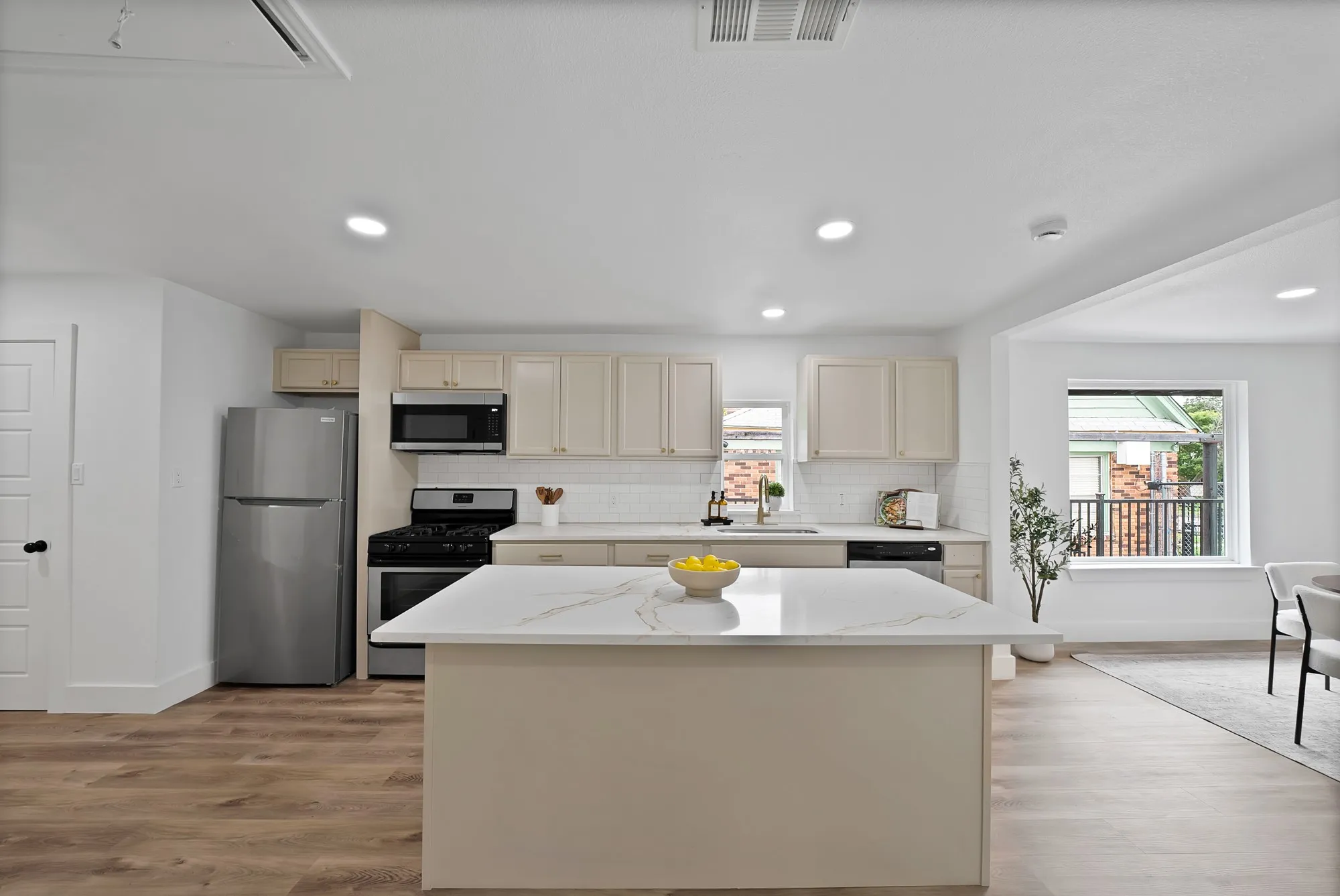 Spacious kitchen featuring an island with a quartz countertop, wood-finish flooring, recessed lighting, stainless steel appliances, and shaker-style cabinetry