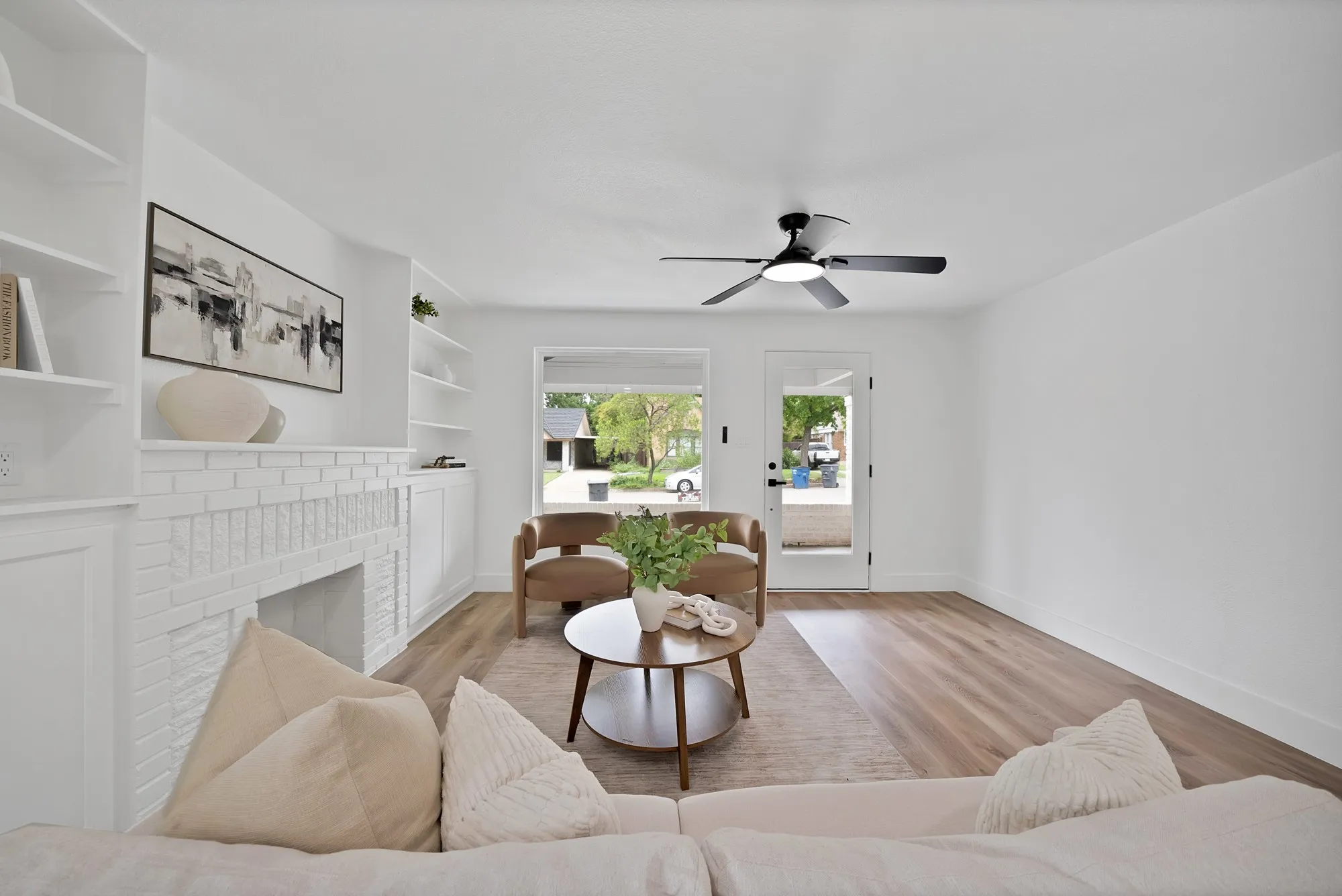 Spacious living area featuring light wood-finish flooring and white walls