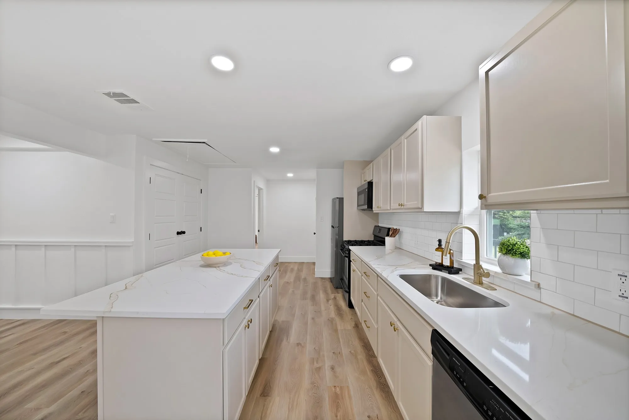 Modern kitchen featuring light-toned cabinetry, a spacious island with a light-toned countertop, wood-finish flooring, recessed lighting, and a subway tile backsplash