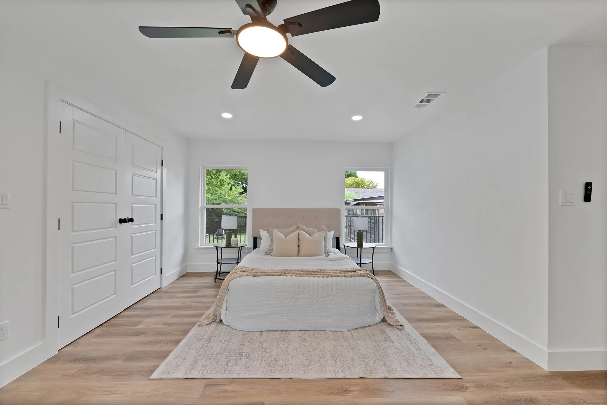 Bright interior space featuring wood-finish flooring, white walls, and a ceiling fan with integrated lighting