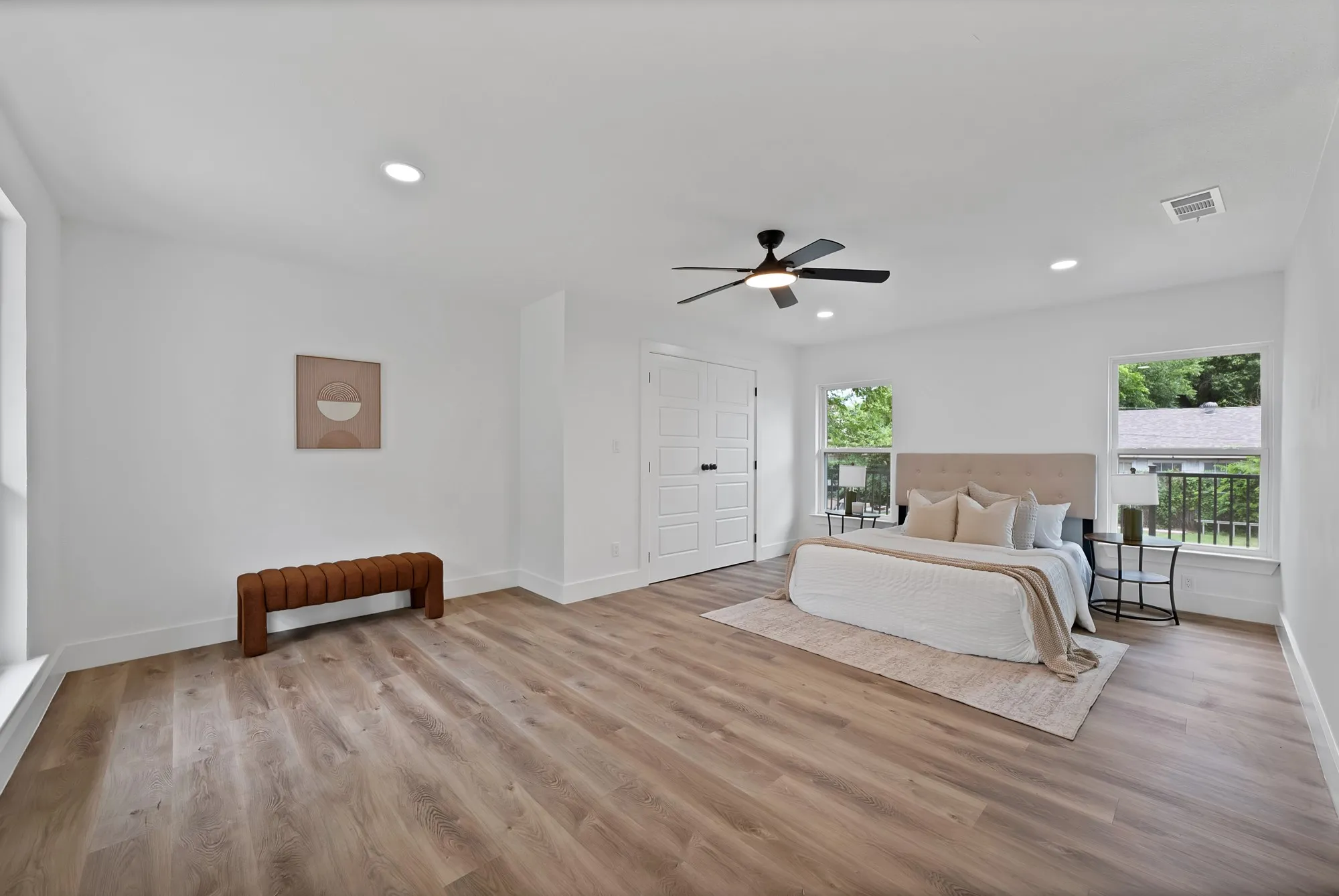 Spacious room featuring wood-finish flooring, white walls, and multiple windows