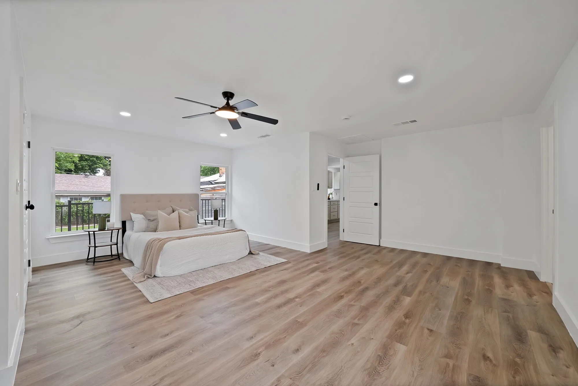 Spacious room featuring wood-finish flooring, recessed lighting, a ceiling fan with light, and two windows