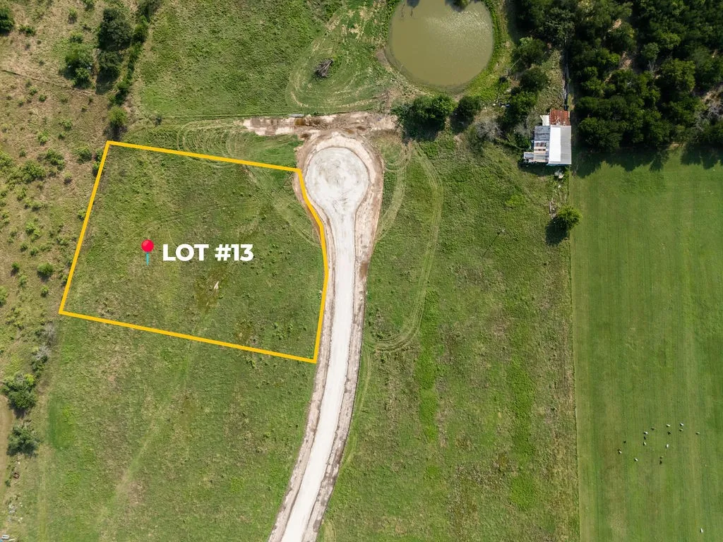 Expansive Lot #13 with verdant green land, bordered by a paved cul-de-sac
