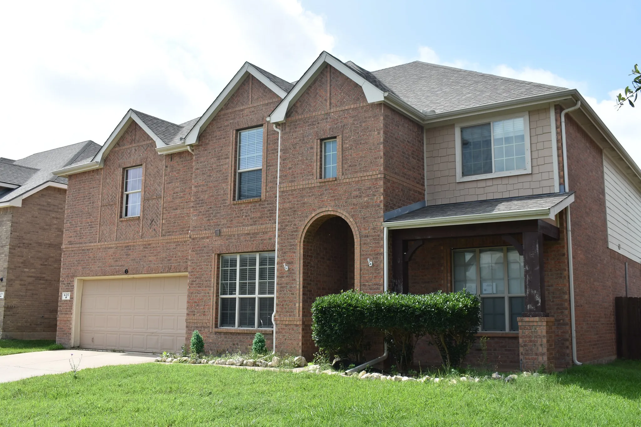Two-story brick exterior with gabled roof lines and a covered entry