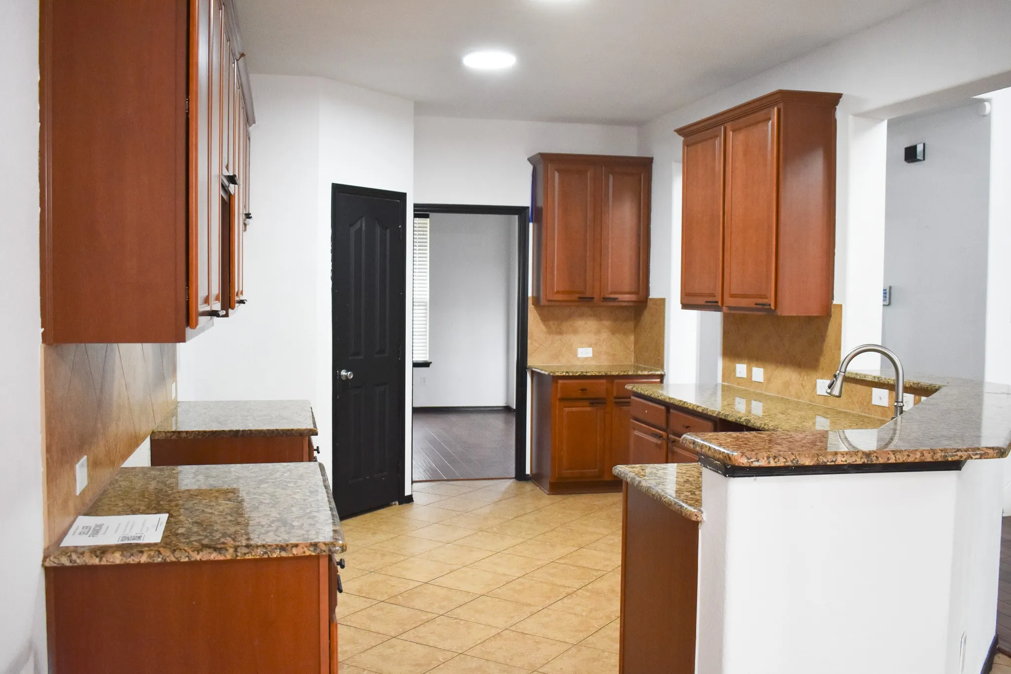 Kitchen featuring extensive cabinetry, ample countertop space, a stainless steel sink with a gooseneck faucet, tiled flooring, and recessed lighting