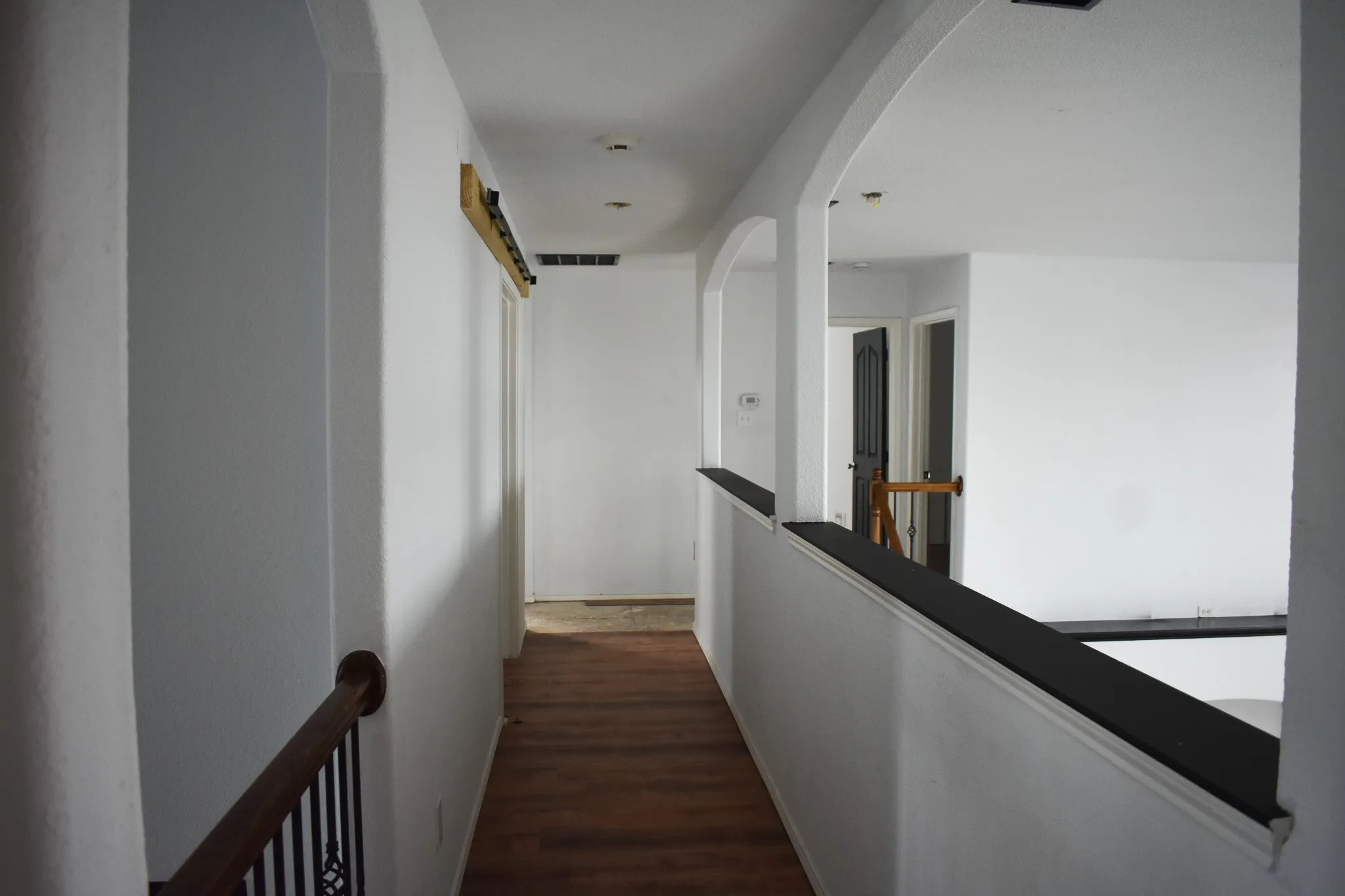 Upper-level hallway featuring wood-finish flooring, white walls, and recessed lighting
