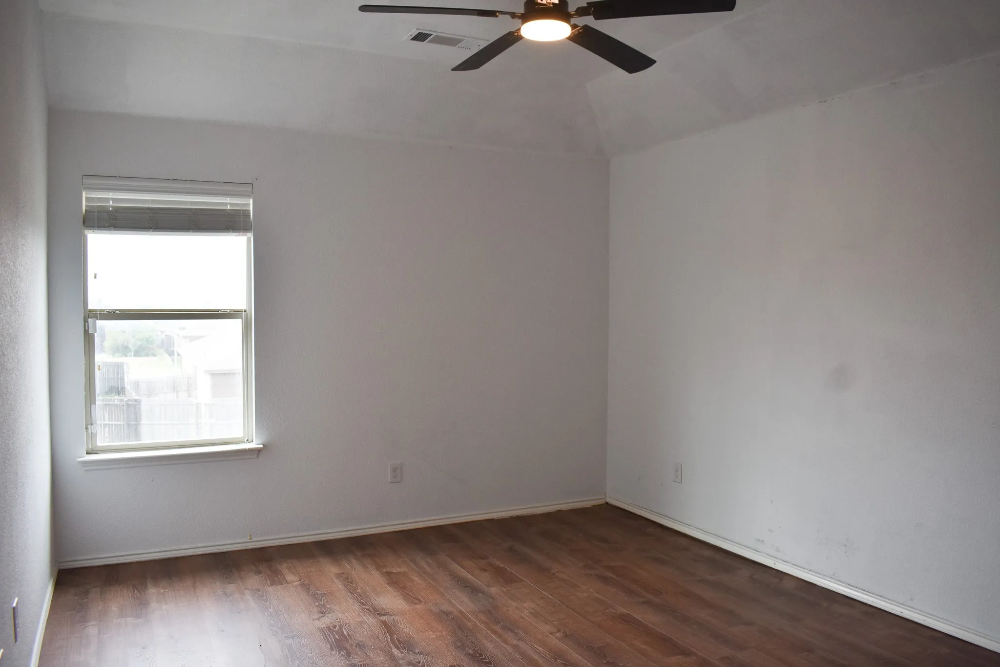 Spacious room featuring vaulted ceilings and wood-finish flooring