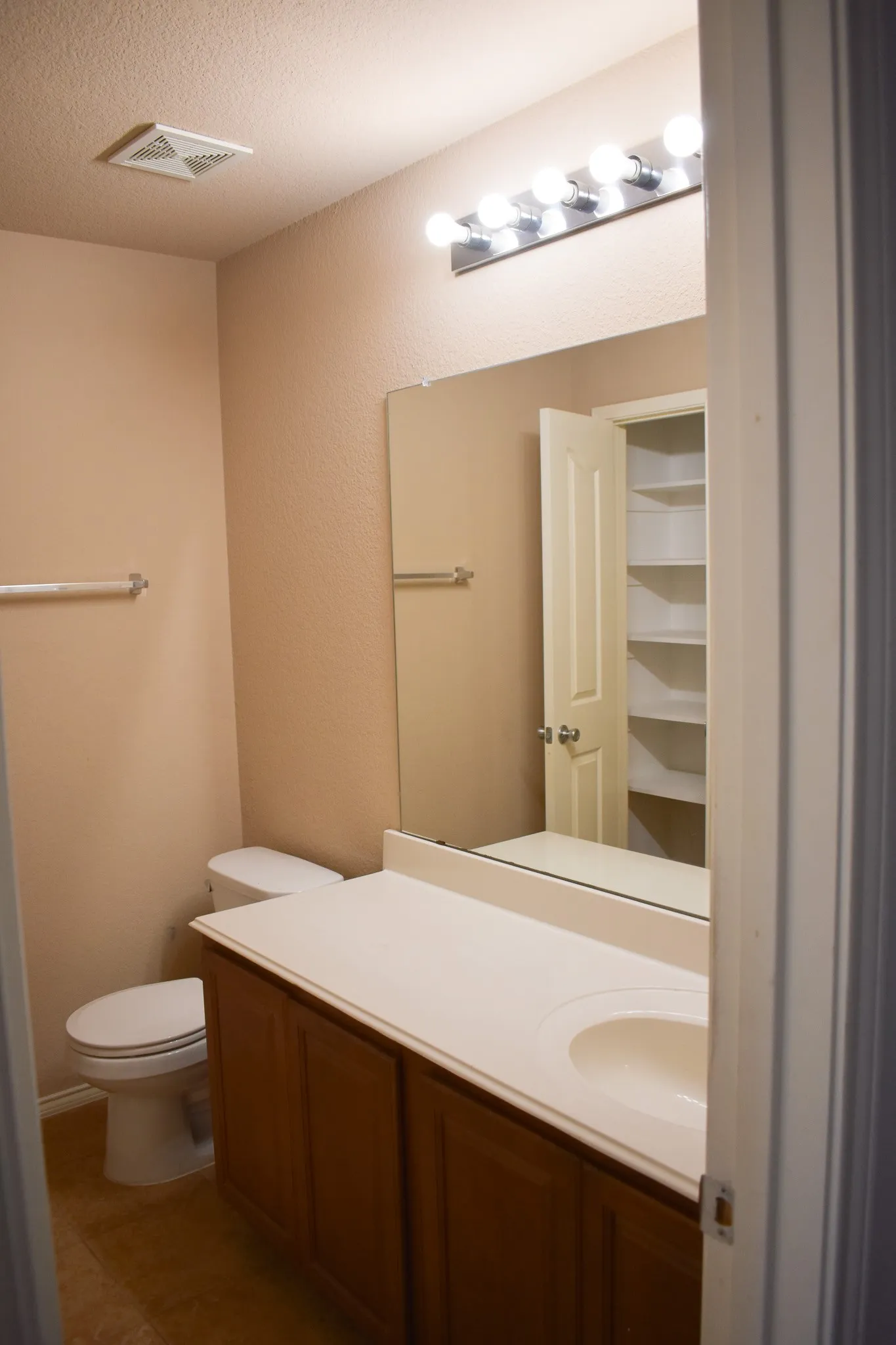 Bathroom vanity featuring a single integrated sink, a light-toned countertop, and wood-panel cabinetry
