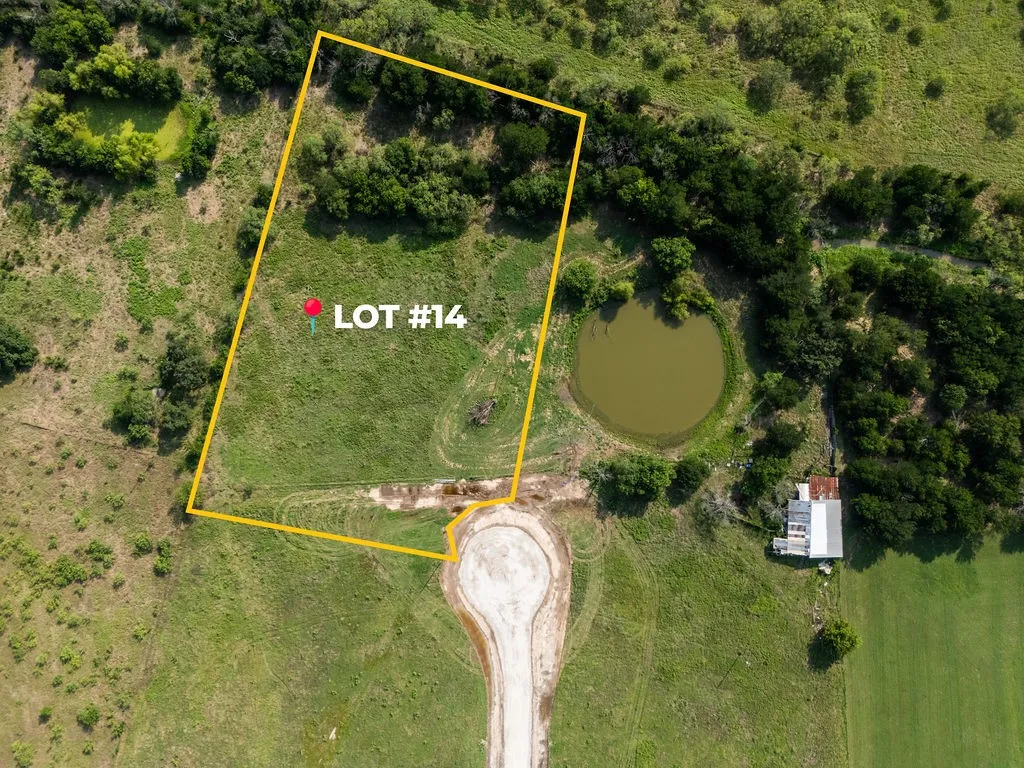 Aerial view of Lot #14, featuring a combination of open grassy areas and mature trees